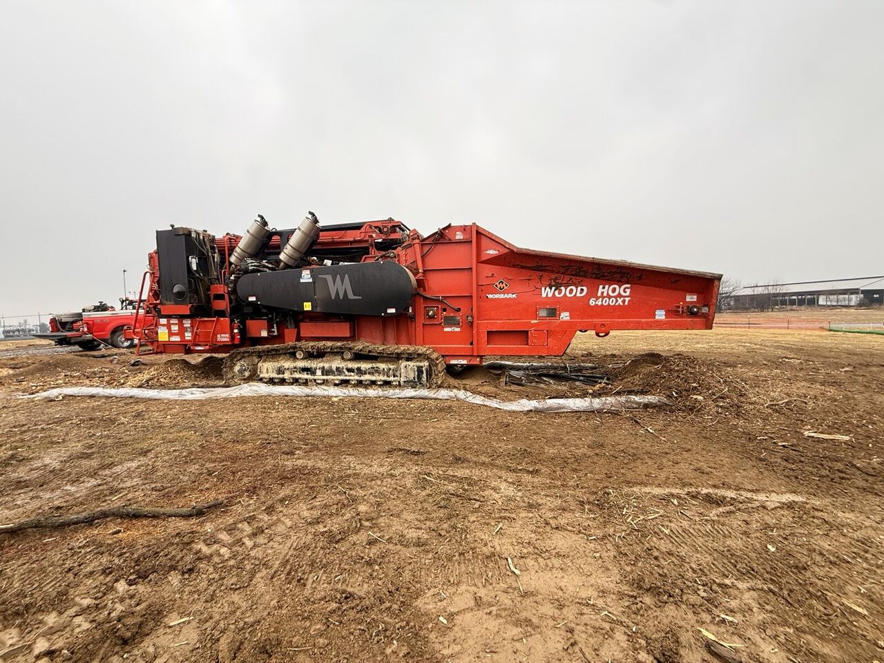 Large horizontal tub grinder staged on a cleared pad processing woody material
